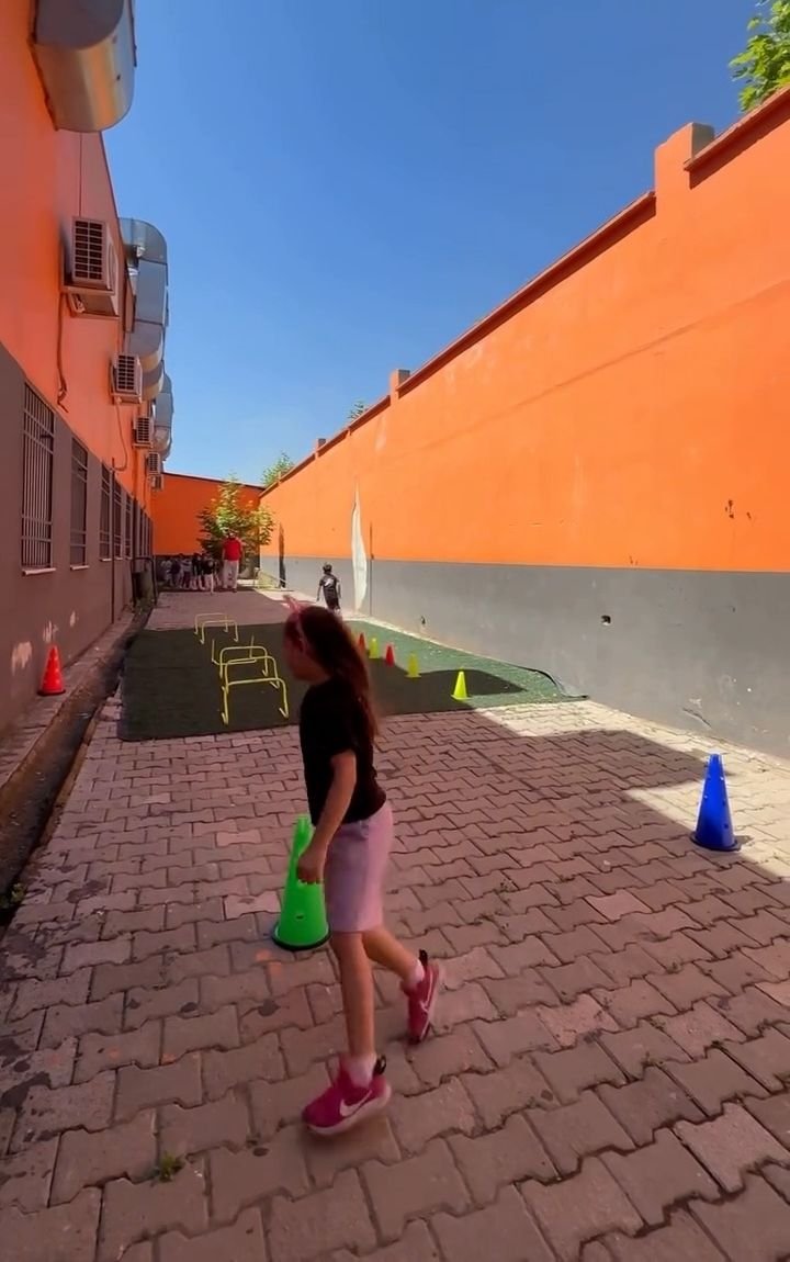 Bahçedeki koni parkurunda koşan anasınıfı öğrencisi